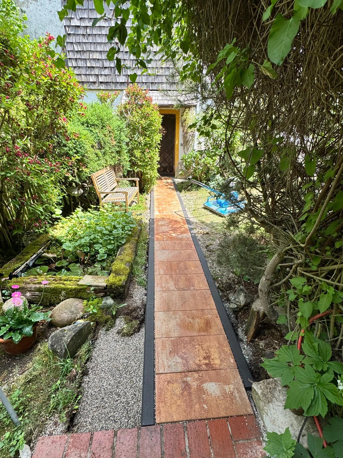 Neu gestalteter Gartenweg mit roten Platten