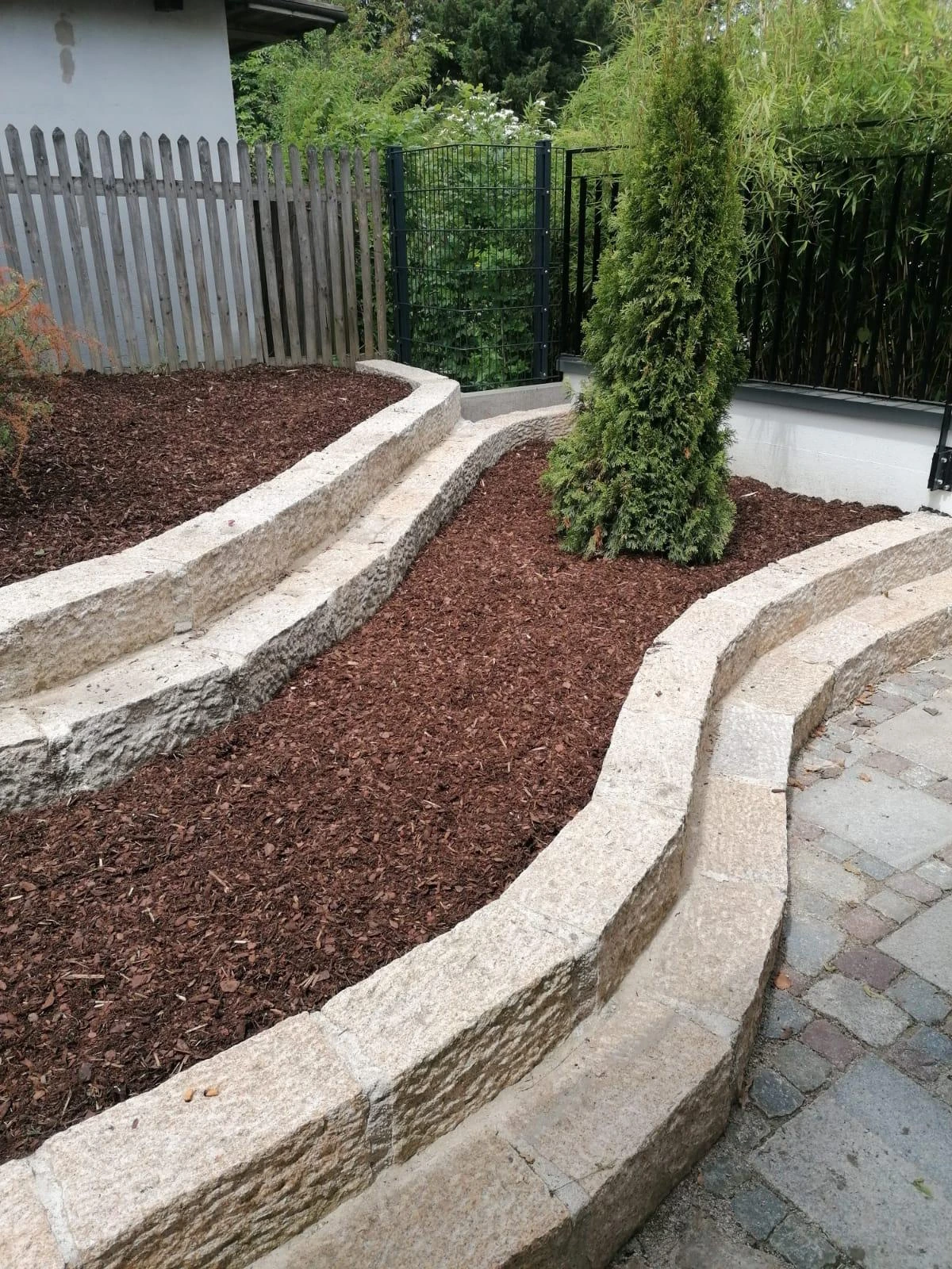 Geschwungene Natursteinmauern mit Pflanzflächen